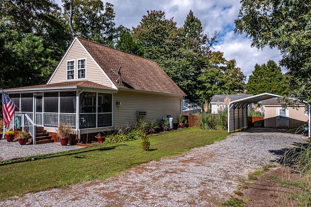 rear view of property with a yard, a sunroom, an outbuilding, and a carport