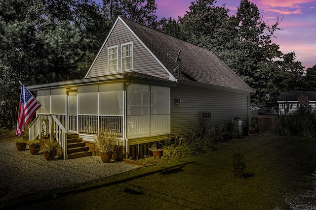 back house at dusk with a sunroom