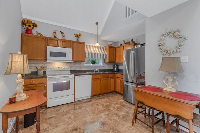 kitchen with decorative backsplash, white appliances, sink, pendant lighting, and lofted ceiling