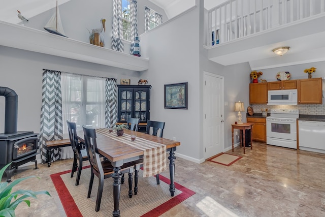 dining area featuring a wood stove and a high ceiling