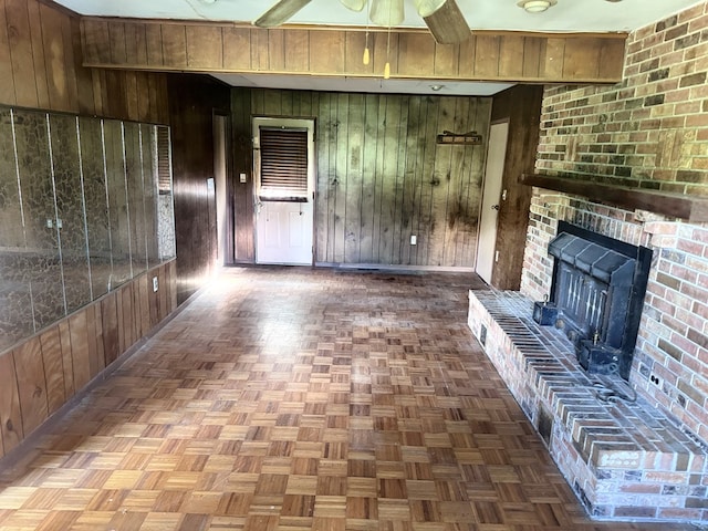 unfurnished living room with wood walls, a ceiling fan, and baseboards