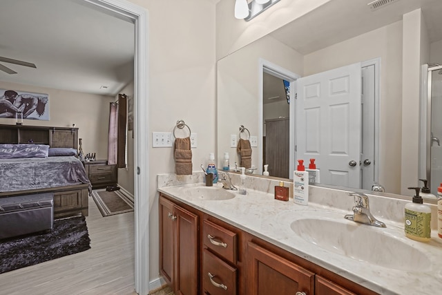 ensuite bathroom featuring double vanity, a sink, a ceiling fan, and connected bathroom