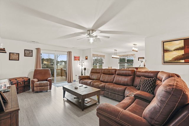 living area featuring ceiling fan with notable chandelier and wood finished floors