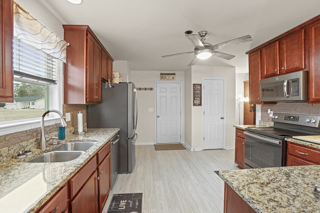 kitchen featuring stainless steel appliances, a sink, backsplash, and light stone counters