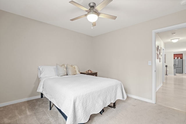 bedroom featuring stainless steel fridge, baseboards, and light colored carpet