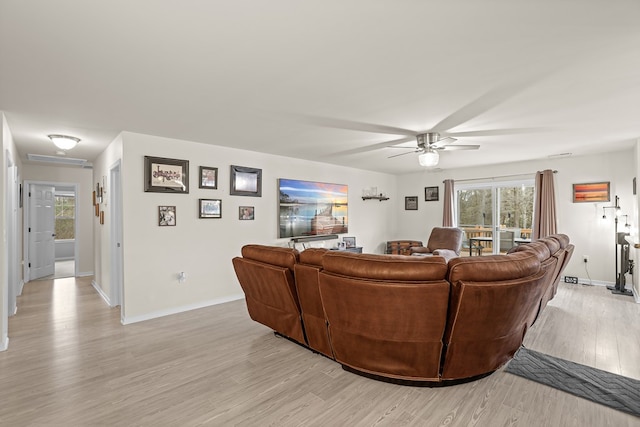 living area featuring light wood-type flooring, a healthy amount of sunlight, ceiling fan, and baseboards