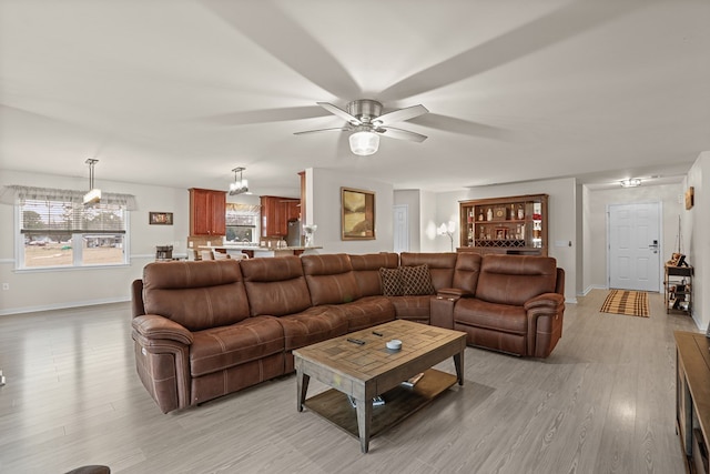 living room with light wood-type flooring, ceiling fan, and baseboards