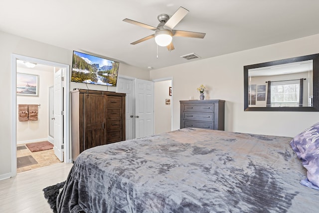 bedroom featuring ceiling fan, ensuite bathroom, visible vents, and baseboards