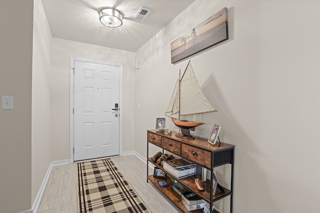 foyer entrance with light wood-style flooring, visible vents, and baseboards