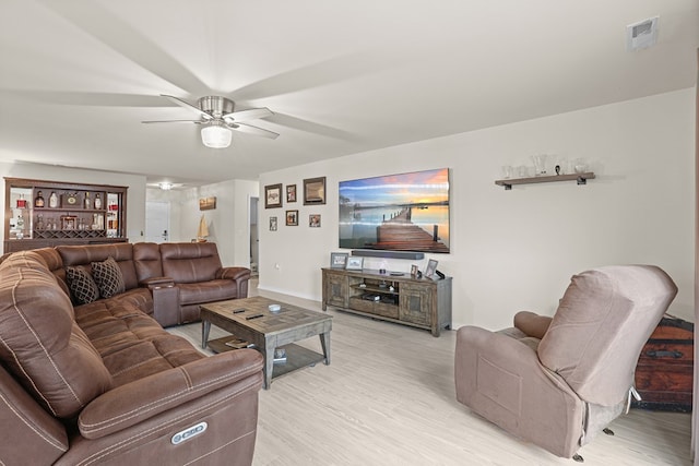 living room featuring visible vents, light wood-style flooring, and a ceiling fan