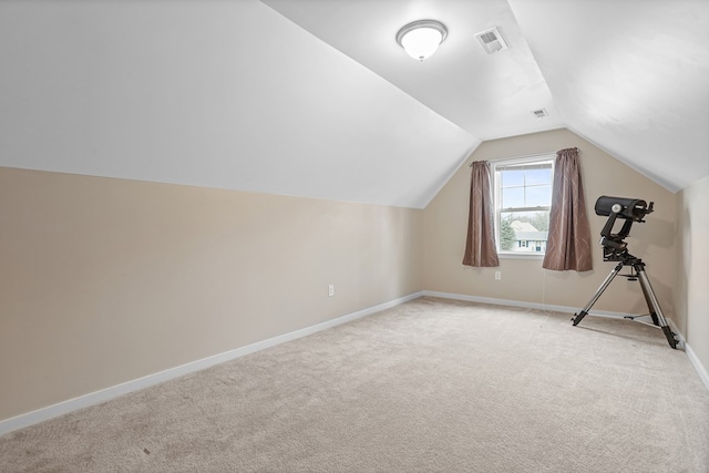 additional living space with lofted ceiling, baseboards, visible vents, and light colored carpet