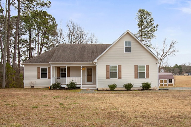 view of front facade with an outbuilding, a porch, roof with shingles, a storage unit, and a front yard