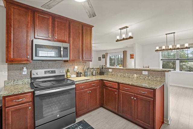 kitchen featuring a peninsula, appliances with stainless steel finishes, light wood-type flooring, and decorative backsplash