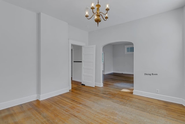 empty room featuring light hardwood / wood-style flooring and a notable chandelier