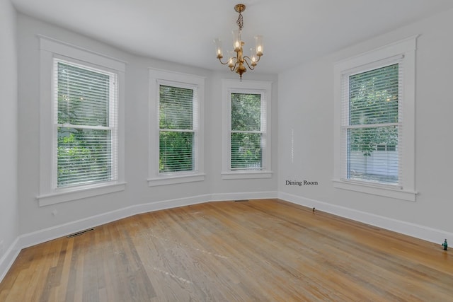 spare room featuring light hardwood / wood-style flooring and a chandelier