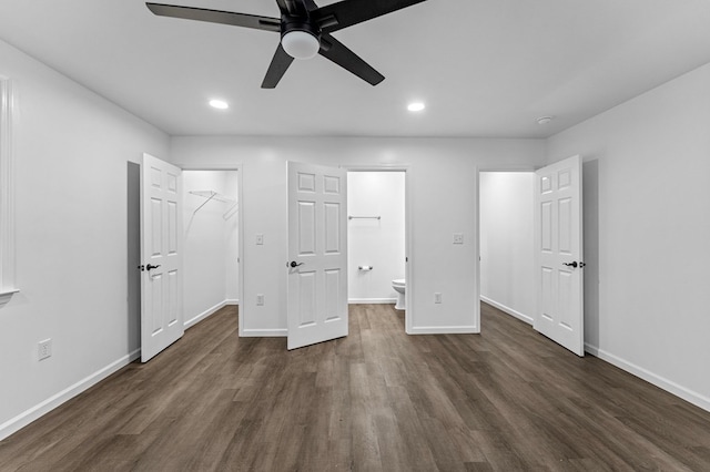 unfurnished bedroom with connected bathroom, ceiling fan, dark hardwood / wood-style floors, a walk in closet, and a closet