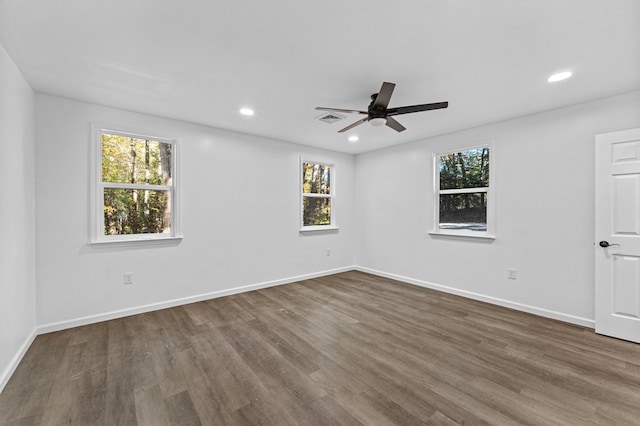 empty room with dark hardwood / wood-style flooring, a wealth of natural light, and ceiling fan