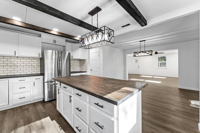 kitchen with decorative backsplash, stainless steel refrigerator, hanging light fixtures, and a kitchen island