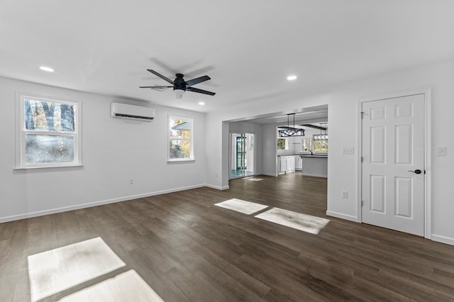 unfurnished living room featuring an AC wall unit, ceiling fan, and dark wood-type flooring