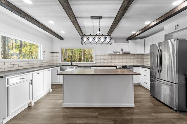 kitchen featuring stainless steel refrigerator, white cabinetry, a kitchen island, and pendant lighting