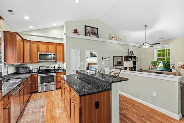 126 Pioneer Trl, Hague, VA 22469 - kitchen with stainless steel appliances, light wood finished floors, a center island, brown cabinets, and dark stone countertops
