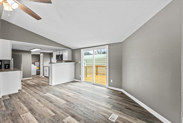 unfurnished living room featuring washer / clothes dryer, vaulted ceiling, light hardwood / wood-style floors, and ceiling fan