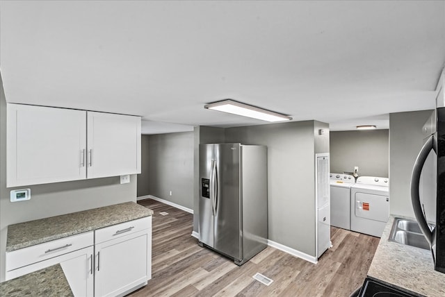 kitchen with white cabinetry, stainless steel fridge, light hardwood / wood-style floors, and independent washer and dryer