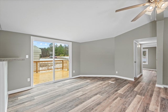 unfurnished room with light hardwood / wood-style flooring, expansive windows, ceiling fan, and vaulted ceiling