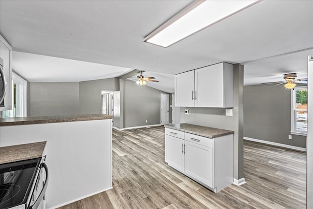 kitchen featuring vaulted ceiling, electric range, light wood-type flooring, ceiling fan, and white cabinets