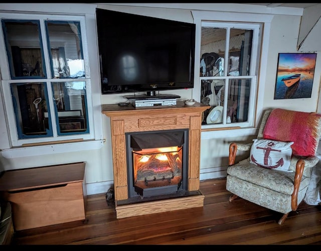 sitting room with a lit fireplace and dark wood finished floors