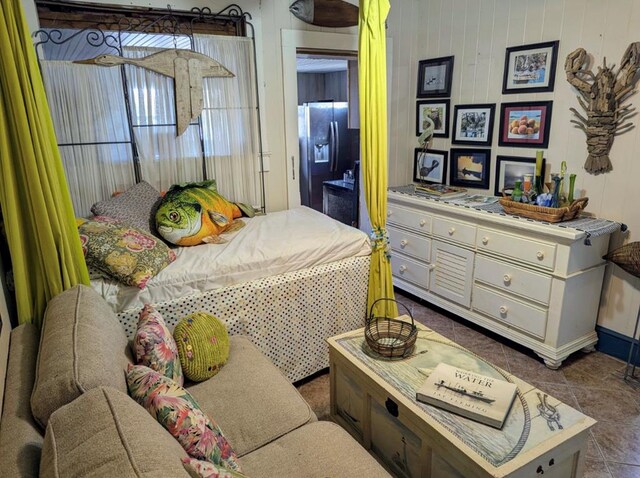 bedroom featuring dark tile patterned flooring and stainless steel refrigerator with ice dispenser