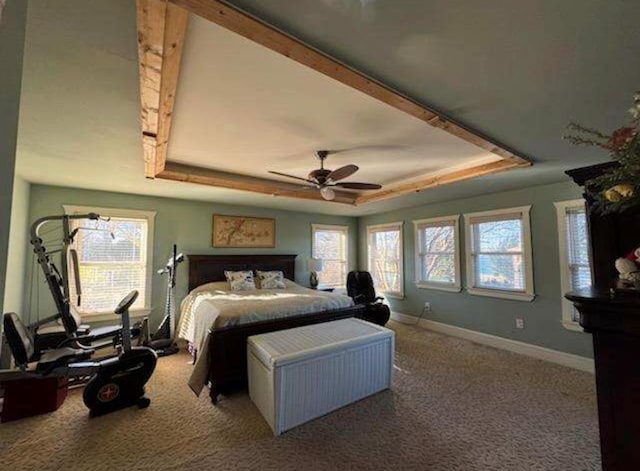 carpeted bedroom featuring a raised ceiling, a ceiling fan, and baseboards