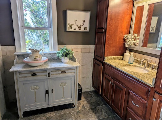 bathroom featuring tile walls, two vanities, and a sink