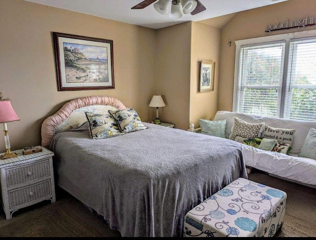 bedroom with lofted ceiling, dark carpet, and ceiling fan