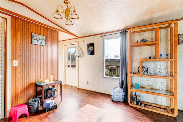 misc room with a wealth of natural light, a notable chandelier, vaulted ceiling, and wood finished floors