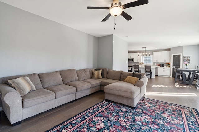 living room with ceiling fan with notable chandelier and dark hardwood / wood-style flooring