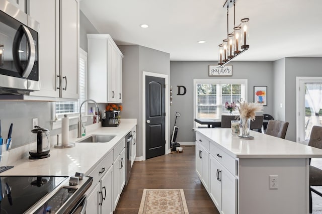 kitchen with white cabinets, a kitchen breakfast bar, sink, appliances with stainless steel finishes, and a kitchen island