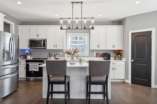 kitchen with white cabinets, decorative light fixtures, a center island, and appliances with stainless steel finishes