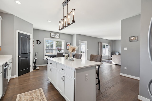 kitchen featuring a kitchen breakfast bar, stainless steel dishwasher, white cabinets, a kitchen island, and hanging light fixtures