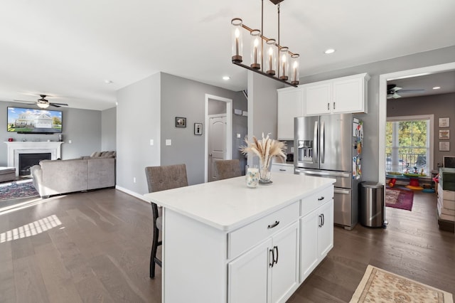 kitchen featuring hanging light fixtures, a kitchen island, stainless steel fridge, a breakfast bar, and white cabinets