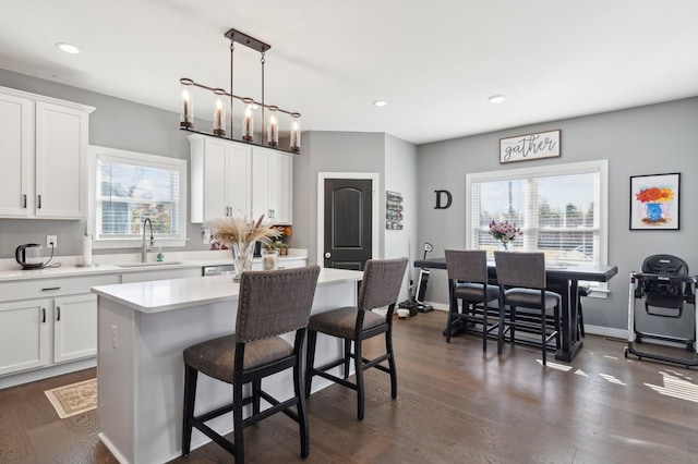 kitchen with pendant lighting, a center island, white cabinetry, and sink