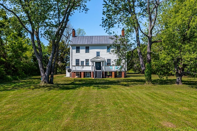 rear view of house featuring a wooden deck and a lawn