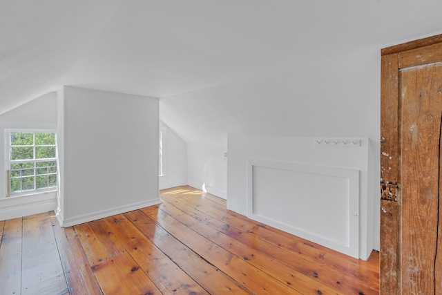 additional living space featuring lofted ceiling and light hardwood / wood-style flooring