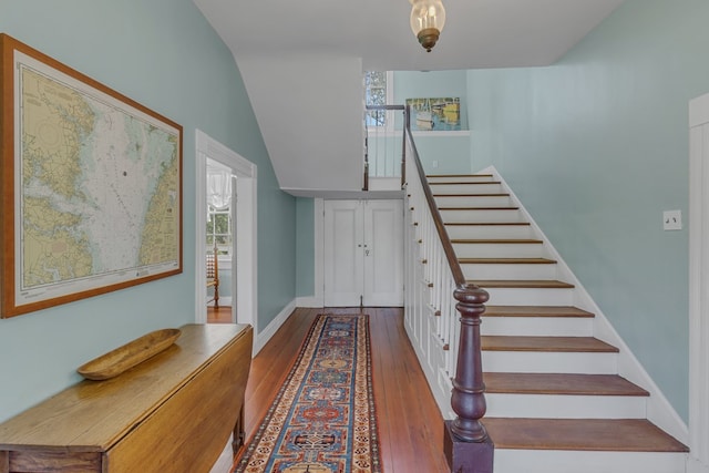 stairs with hardwood / wood-style flooring, lofted ceiling, and a healthy amount of sunlight