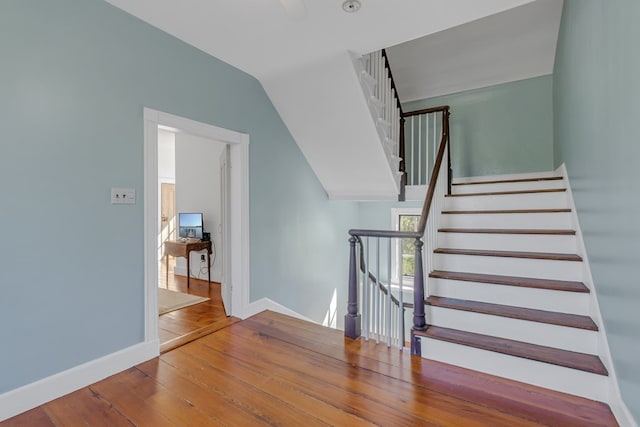 staircase with hardwood / wood-style flooring and lofted ceiling