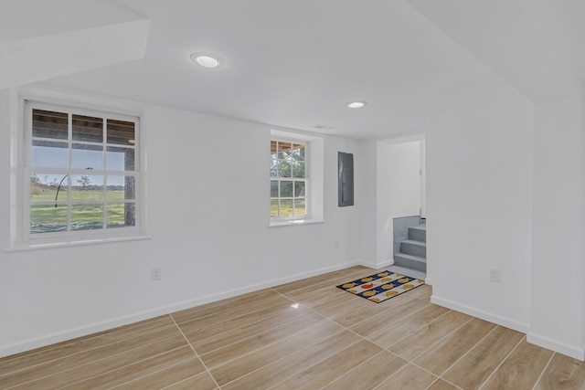 unfurnished living room with electric panel and light hardwood / wood-style floors