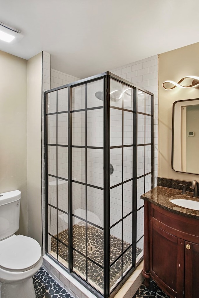 bathroom with tile patterned floors, vanity, toilet, and a shower