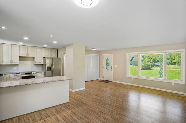 kitchen featuring light stone counters, appliances with stainless steel finishes, and light hardwood / wood-style flooring