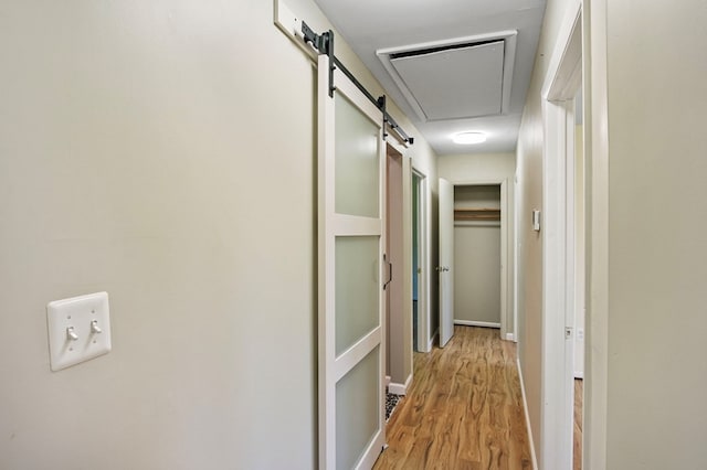 corridor with a barn door and light hardwood / wood-style floors