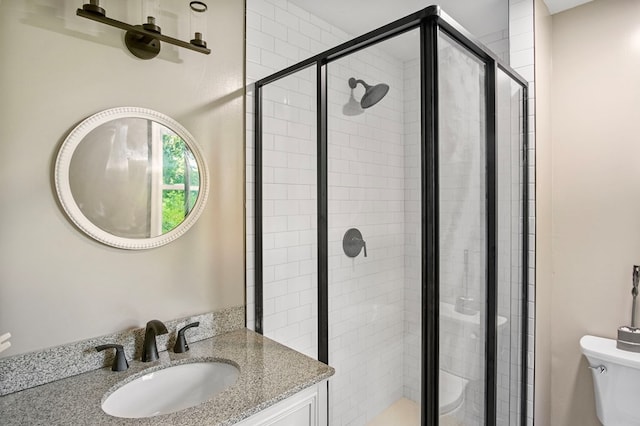 bathroom featuring vanity, toilet, and a shower with door